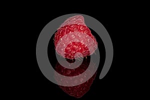 Fresh red raspberry isolated on black glass