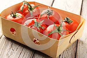 Fresh, red, ripe tomatoes in a box on a light