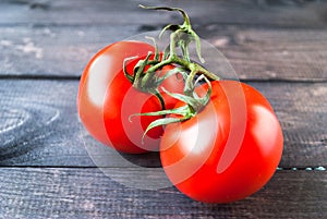 Fresh red ripe tomatoes on a branch on a wooden background