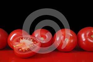 Fresh red Roma tomatoes on red table and black background, copy