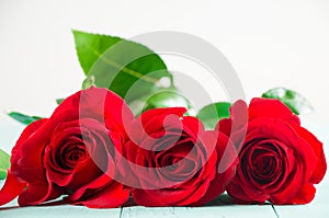 Fresh red roses on a aquamarine table