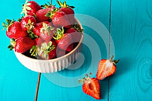 Fresh red strawberries in the bowl in blue wooden background. Copy space, top view.