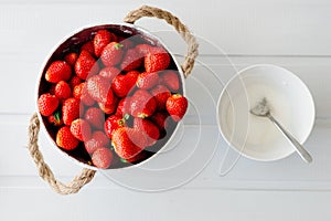 Fresh red strawberries in white bowl and sugarbowl