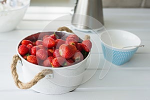 Fresh red strawberries in white bowl and sugarbowl