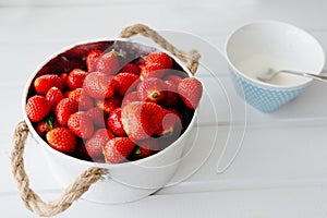 Fresh red strawberries in white bowl and sugarbowl