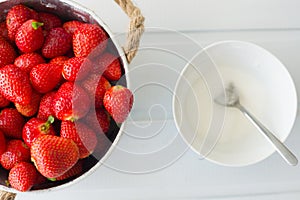 Fresh red strawberries in white bowl and sugarbowl