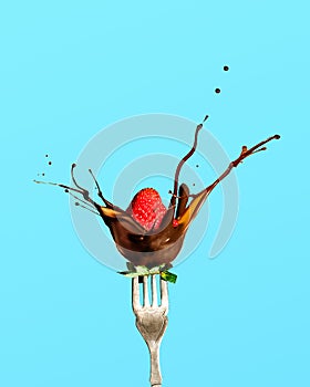 fresh red strawberry dipped in chocolate on fork isolated over bright blue background
