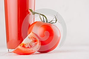 Fresh red tomato drink and pulpy tomato with juicy piece on light soft white wood table, copy space, closeup.