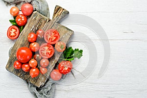 Fresh red tomatoes on white wooden background. Greens. Top view