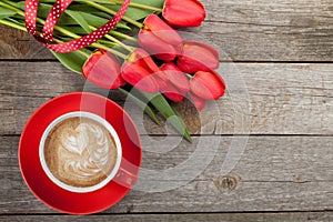 Fresh red tulips with ribbon and coffee cup with heart shape