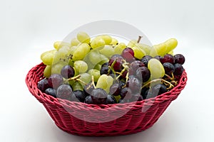 Fresh Red and White Grapes in a red basket isolated on white background