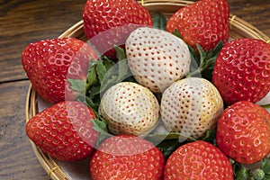 Fresh Red and White strawberries with leaves on bamboo basket, Red and White strawberry from in Bamboo basket on wooden table.