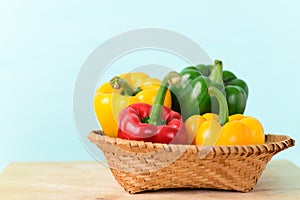 Fresh red, yellow and green bell peppers in a bamboo basket