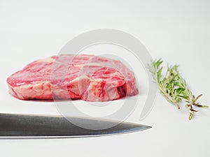 Fresh rib eye beef steak, on white surface.
