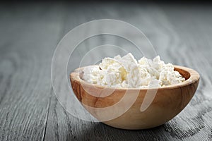 Fresh ricotta in olive wood bowl on old table