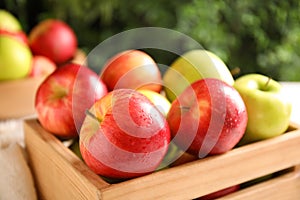 Fresh ripe apples in wooden crate on blurred background, closeup