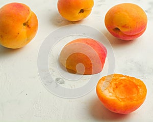 Fresh and ripe apricots on a white stone background.