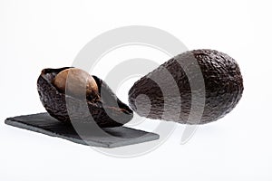 Fresh and ripe avocado next to rotting avocado cut in half with seed visible isolated on white