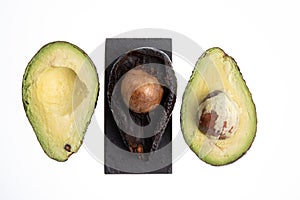 Fresh and ripe avocado next to rotting avocado cut in half with seed visible isolated on white