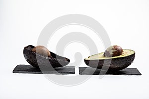 Fresh and ripe avocado next to rotting avocado cut in half with seed visible isolated on white