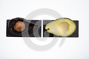 Fresh and ripe avocado next to rotting avocado cut in half with seed visible isolated on white