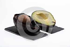Fresh and ripe avocado next to rotting avocado cut in half with seed visible isolated on white