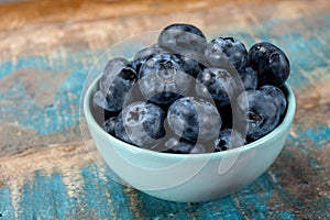 Fresh ripe blueberries in bowl on wooden background