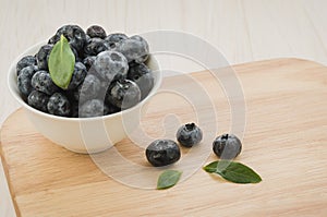 Fresh ripe blueberries with leaves in bowl on wooden tray/Fresh ripe blueberries with leaves in bowl on wooden tray. selective