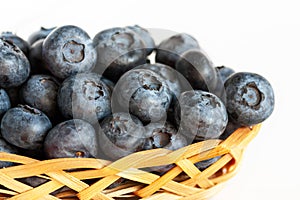Fresh ripe blueberries in a small wicker basket on a white background. Close-up