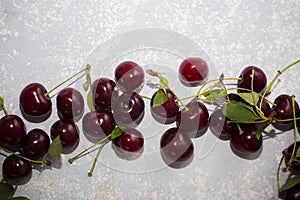 Fresh ripe cherries with leaves on grey table