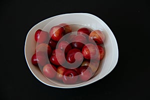 Fresh ripe cherries in a white plate on a black background. Healthy food. Vegetarian breakfast