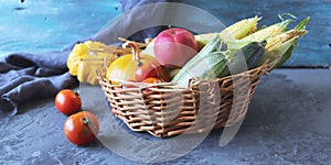 Fresh ripe diverse vegetables and fruits in a basket, on a dark background, organic natural food