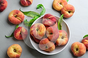 Fresh ripe donut peaches with leaves on light table, flat lay