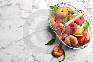 Fresh ripe donut peaches with leaves on white marble table, flat lay. Space for text