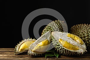 Fresh ripe durian fruits on wooden table against black background