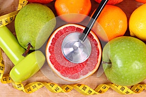 Fresh ripe fruits, tape measure, stethoscope and dumbbells for fitness, healthy lifestyles concept