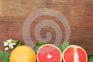 Fresh ripe grapefruits and green leaves on wooden table, flat lay. Space for text