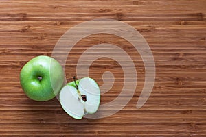 Fresh ripe green apple Granny Smith: whole and sliced in half on a wooden cutting board. Nature fruit concept.