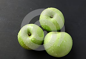Fresh ripe green apple with water drops on wooden table.