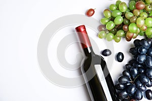 Fresh ripe juicy grapes, bottle of red wine and space for text on white background