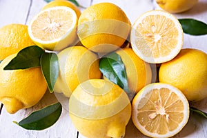 Fresh and ripe lemons with leaves on white wooden table