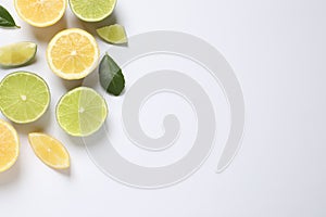 Fresh ripe lemons, limes and green leaves on white background, top view