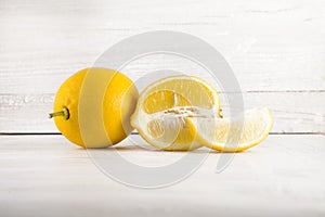 Fresh ripe lemons, slices, rustic food photography on white wood plate kitchen table