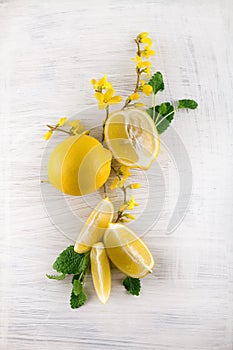 Fresh ripe lemons, slices, rustic food photography on white wood plate kitchen table