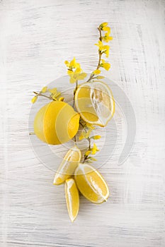 Fresh ripe lemons, slices, rustic food photography on white wood plate kitchen table