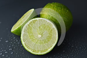 Fresh ripe limes on dark background with water drop