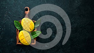 Fresh ripe mango on black stone background. Tropical fruits. Top view.