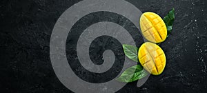 Fresh ripe mango on black stone background. Tropical fruits. Top view.