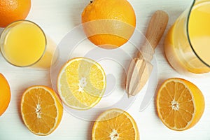 Fresh ripe oranges, juice and reamer on white wooden table, flat lay