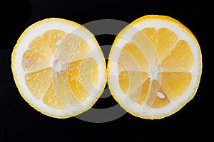 Fresh Ripe Organic Lemon cut in half isolated on black. Citrus Limon. Rutaceae family.